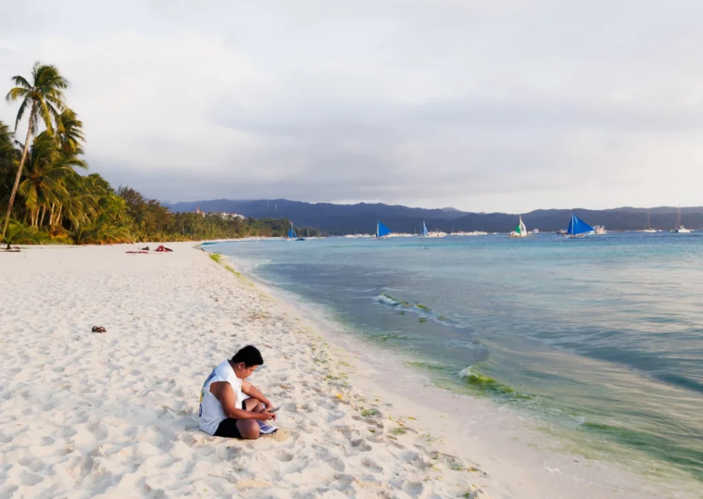 Person reflecting alone on a beach while feeling lost or behind in their career