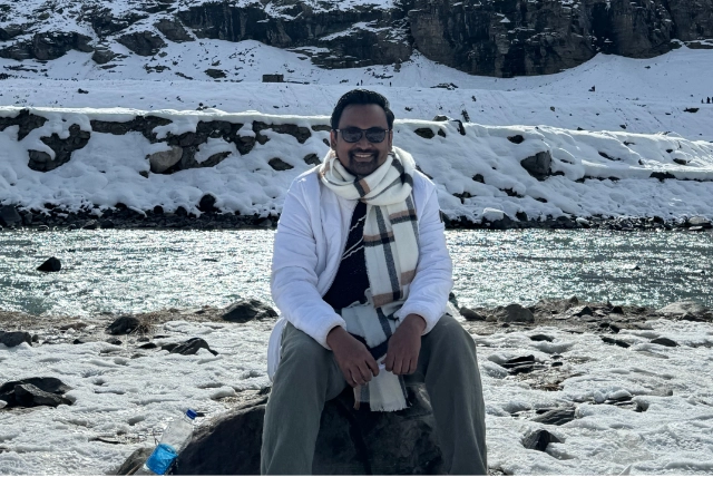 36-year-old man smiling in front of snowy mountains, symbolizing peace, resilience, and the journey of late bloomers.