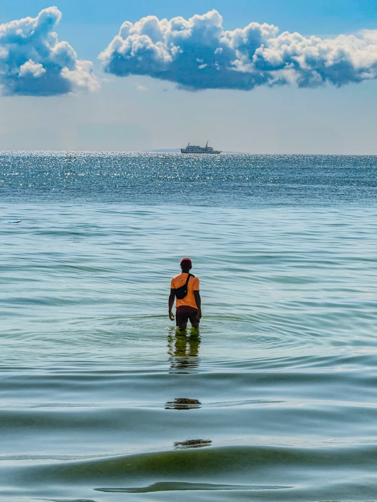 Man standing alone in the ocean and looking towards the horizon, reflecting on whether 30 is too late to start over